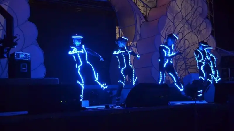 LED tron dancers in glowing blue light-strip suits dancing on a festival stage