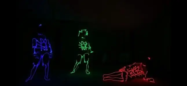 Three tron dancers in blue, green and red light-up suits on a dark stage